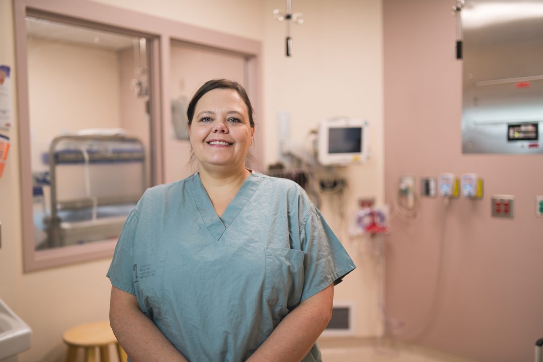 Gillyan Gravelle, registered nurse at Health Sciences North, smiles in a surgical room at Health Sciences North, wearing srubs.